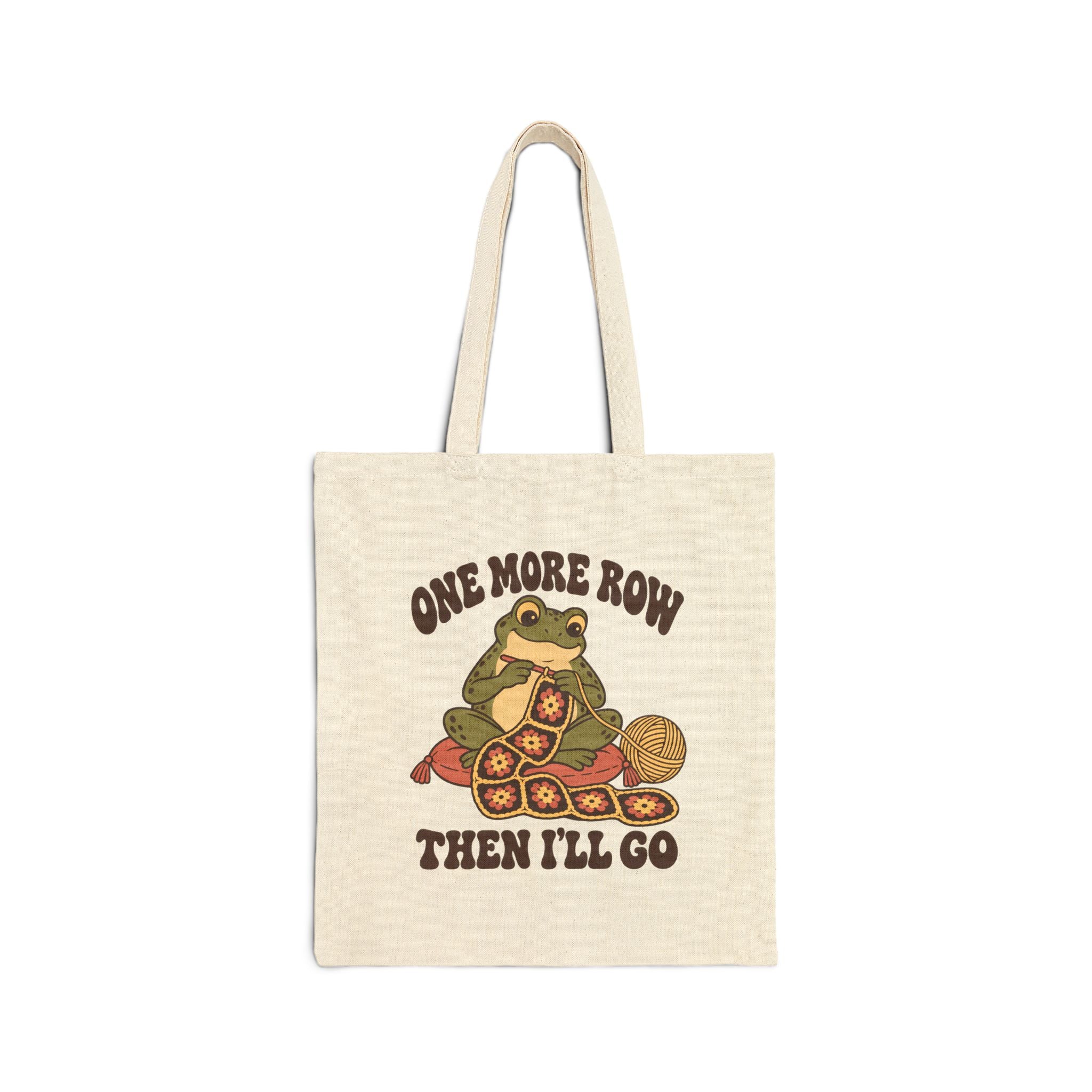 Doğal krem kanvas tote çanta üzerinde örgü ören yeşil kurbağa, çiçek motifli battaniye, sarı ip yumağı ve “One More Row Then I’ll Go” yazısı.